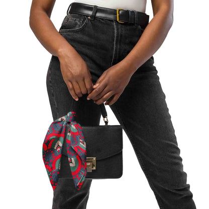 A woman holding a black handbag with a scallop pattern red navy bandana scarf draped over it
