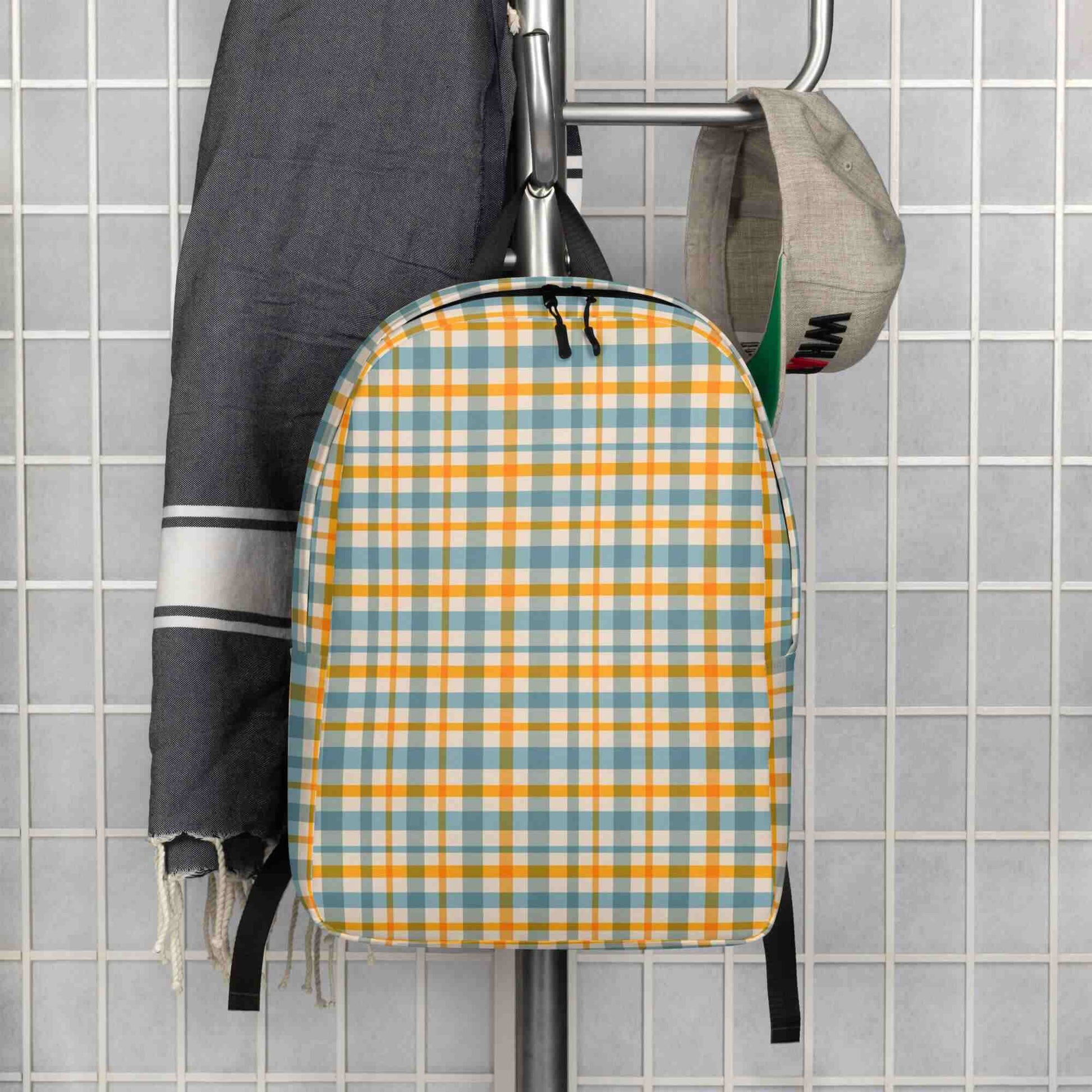 yellow plaid backpack for women hanging on a rack against a tiled wall.