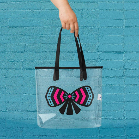 Clear tote bag with a colorful ribbon bow design held against a blue brick wall.