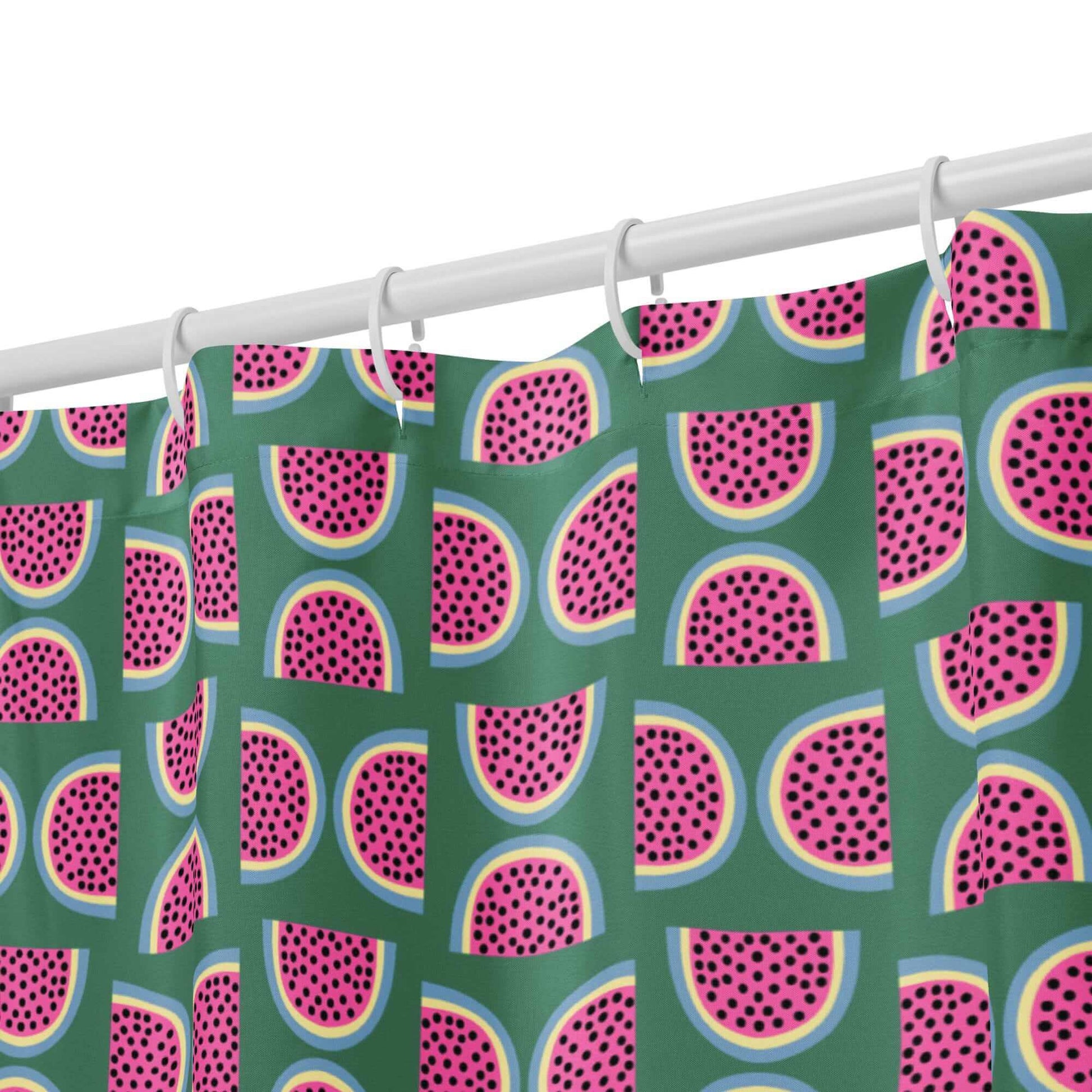green shower curtain with pink watermelon pattern hanging from hooks close up