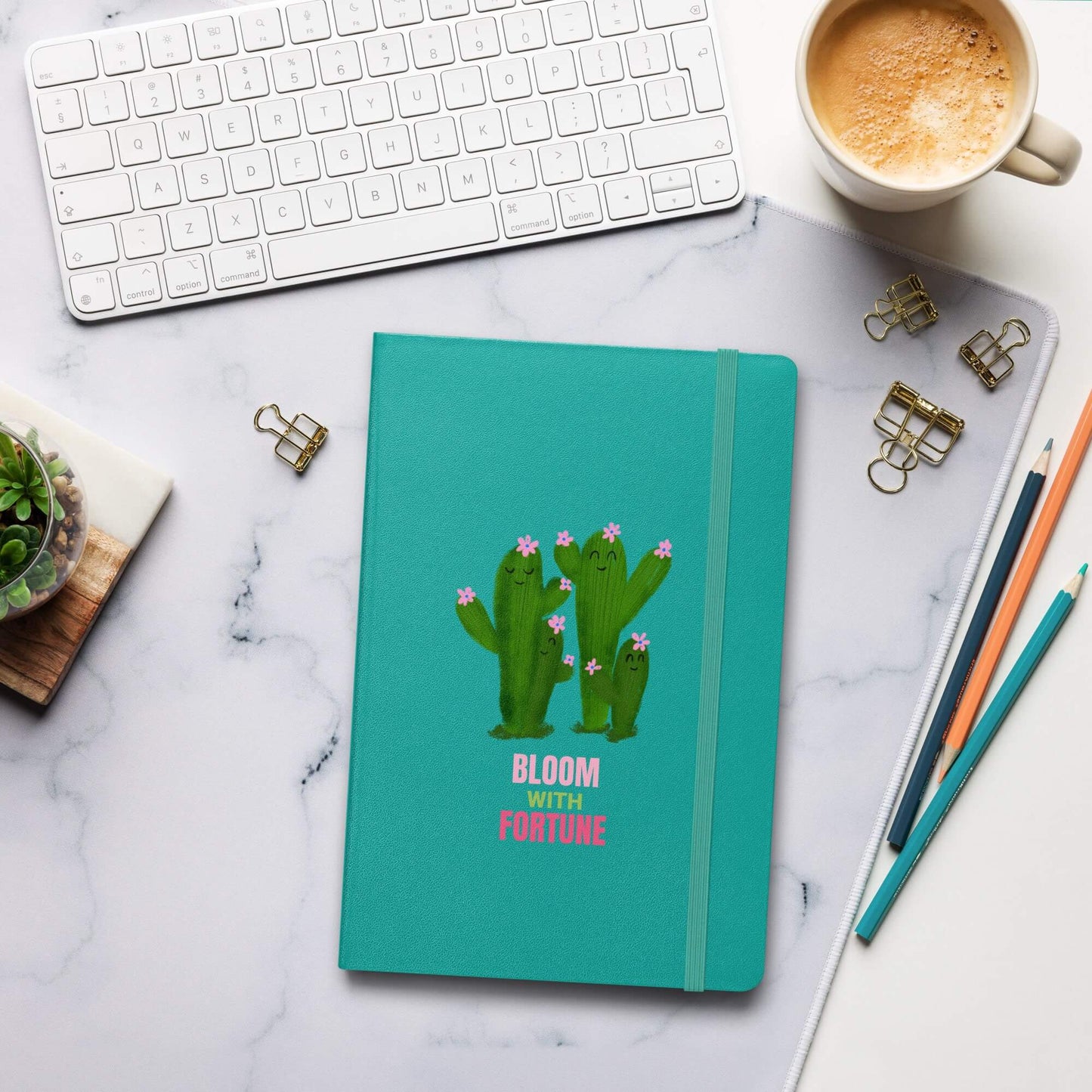 Personalized teal hardcover bound notebook with cactus design on a marble desk with office supplies