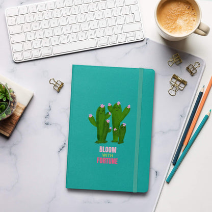 Personalized teal hardcover bound notebook with cactus design on a marble desk with office supplies