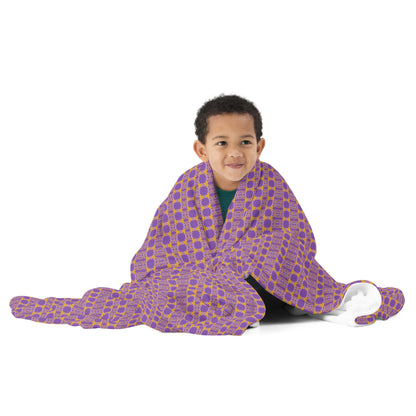 Child wrapped in a purple blanket with yellow patterns on a white background