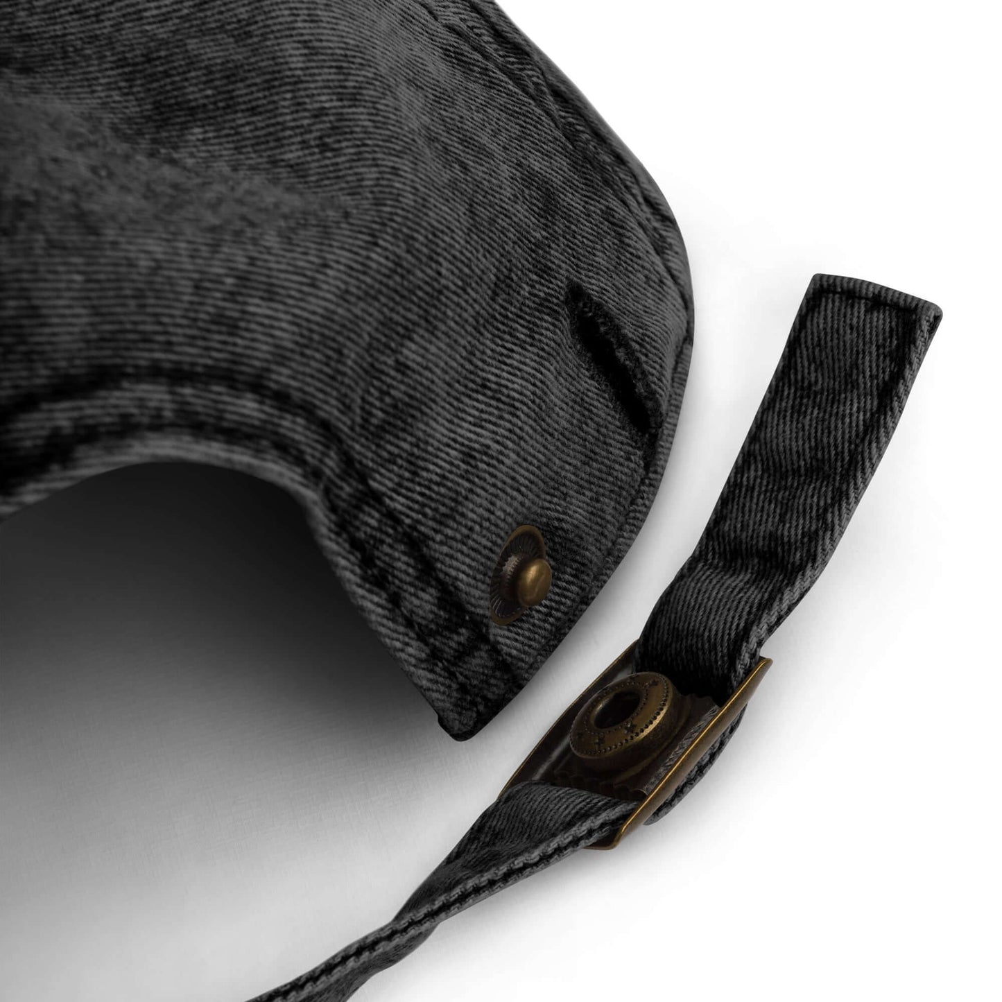 Close-up of a black cotton twill cap with brass buttons and straps on a white background
