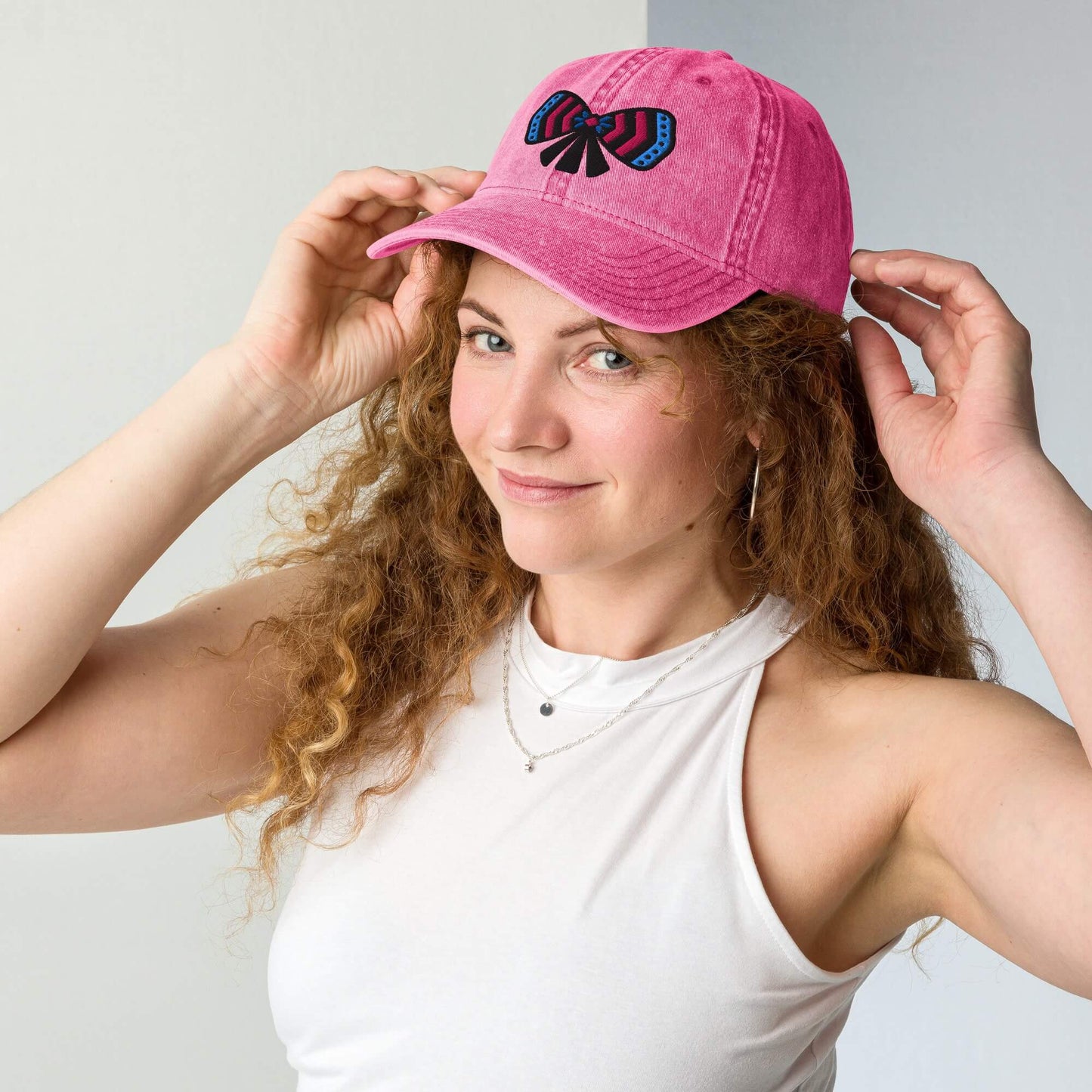 Woman wearing an one owl artist designed pink cotton twill cap with a colorful ribbon bow embroidery