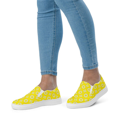 Yellow floral sneakers worn with blue jeans on a white background